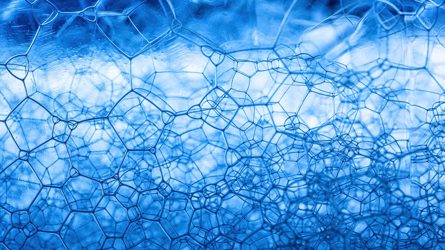 Detailed close-up of blue soap foam showcasing abstract geometric patterns and texture.