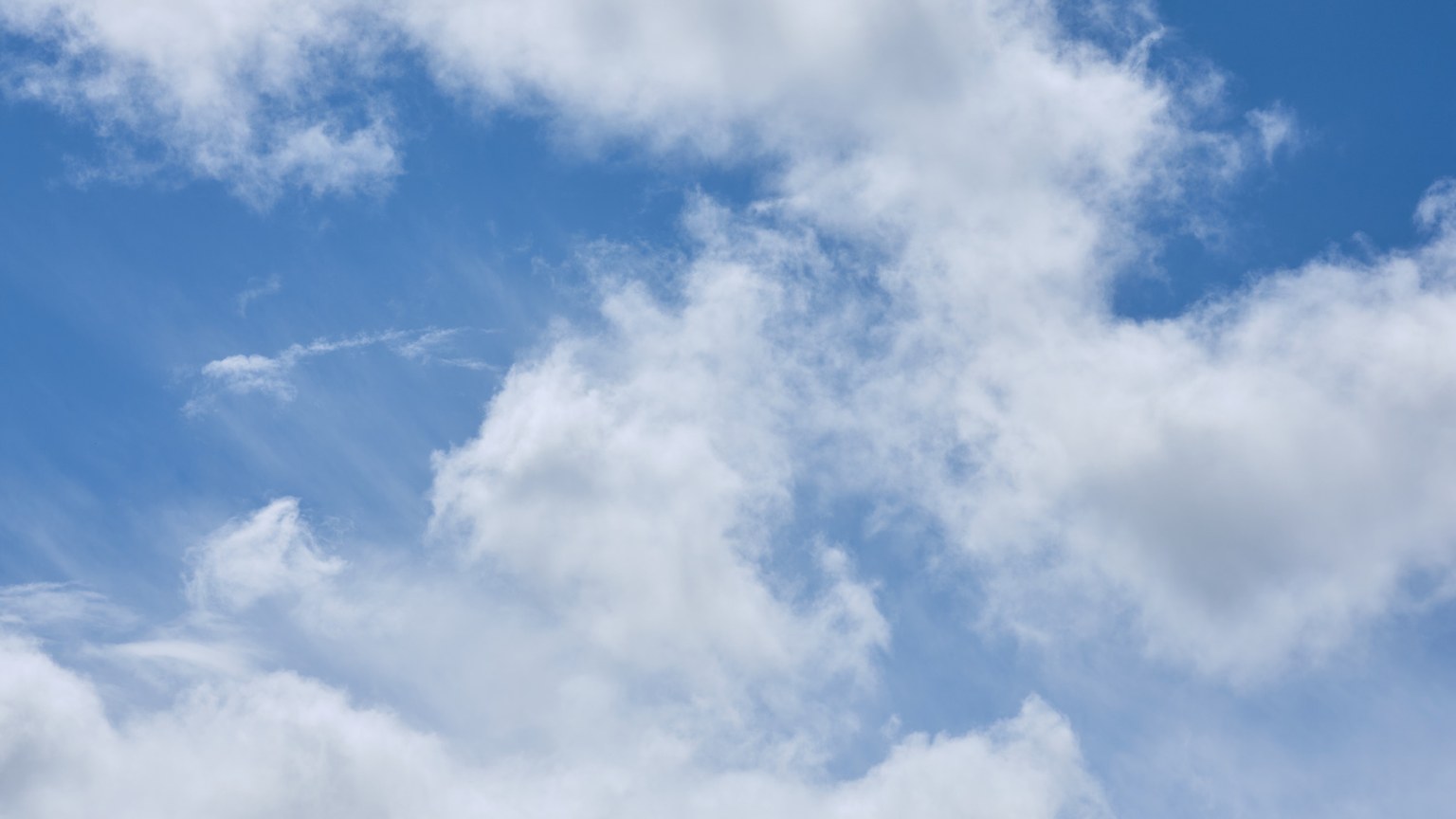 A serene view of fluffy white clouds against a bright blue sky, captured in Penrith, England.