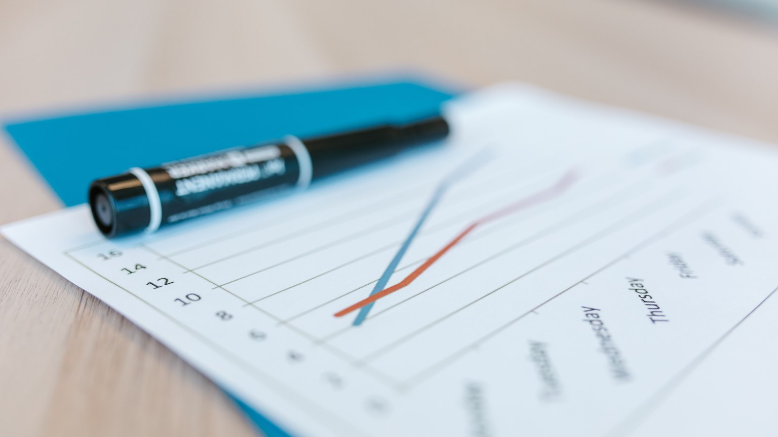Dynamic line chart on paper with black marker on a desk, illustrating data trends.