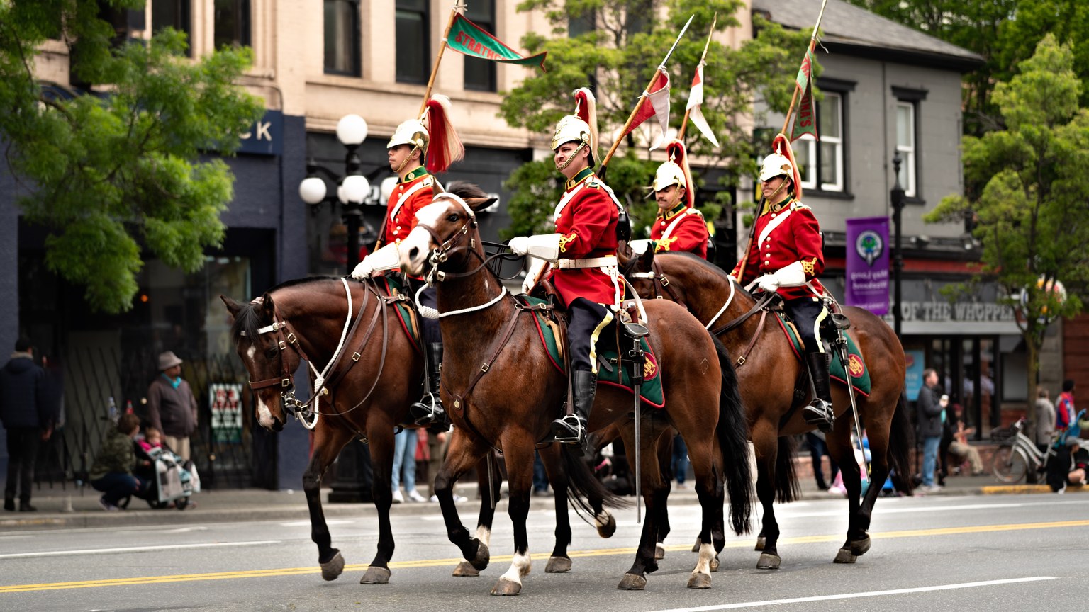 Elegant cavalry procession with soldiers in red uniforms on horses during a city parade.