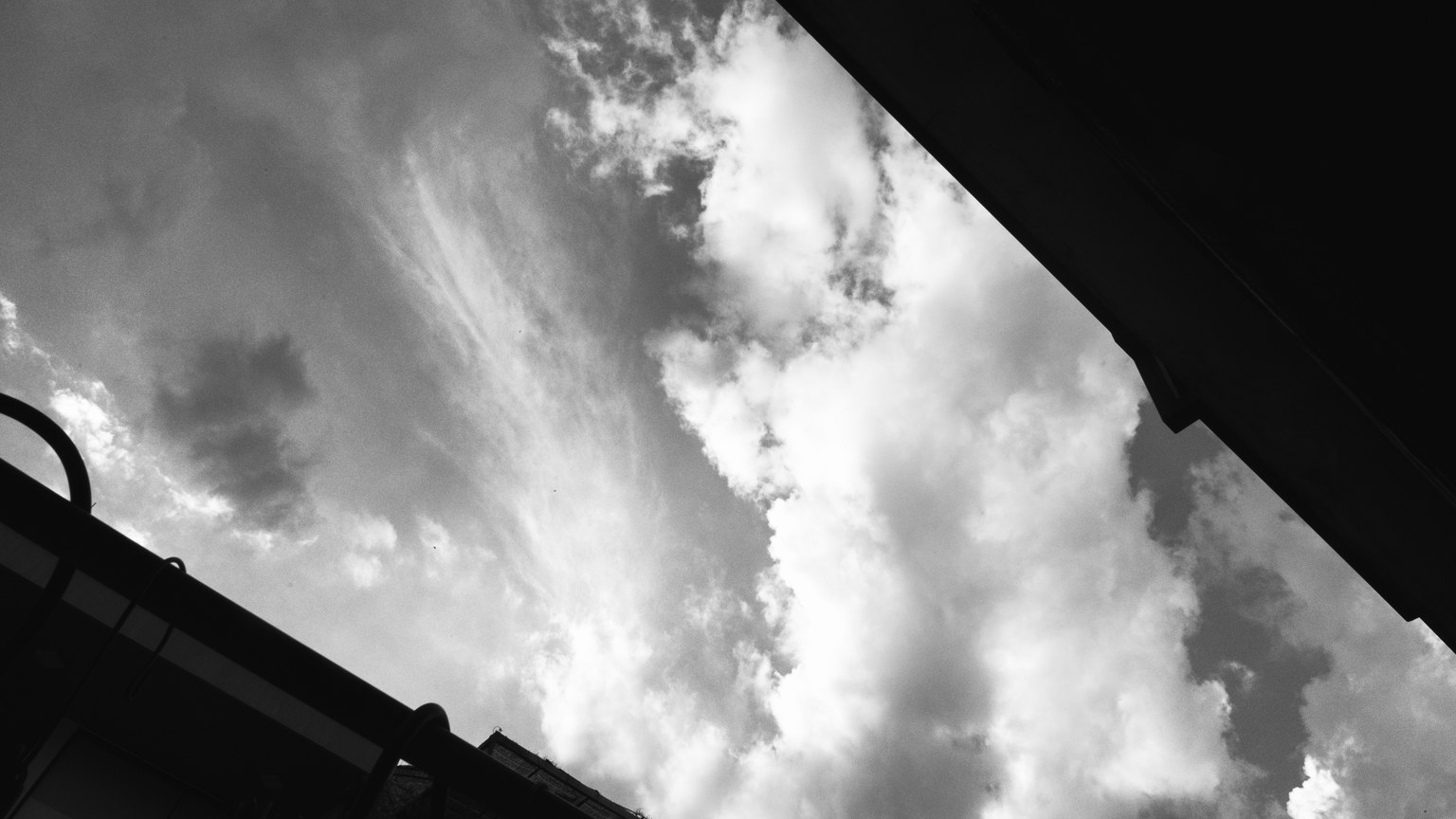 Black and white sky with dramatic clouds and building silhouettes.