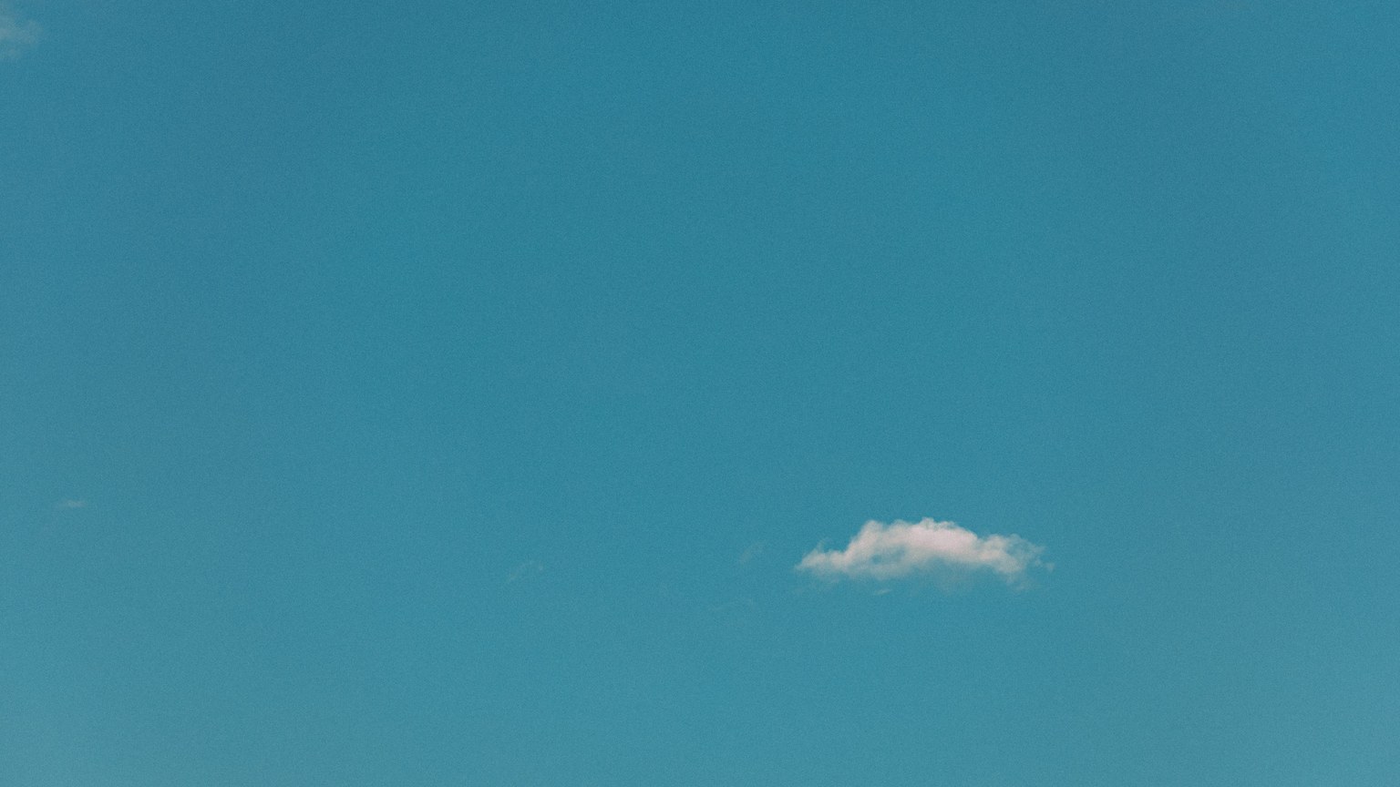 A tranquil blue sky featuring a single white cloud, epitomizing simplicity and serenity.