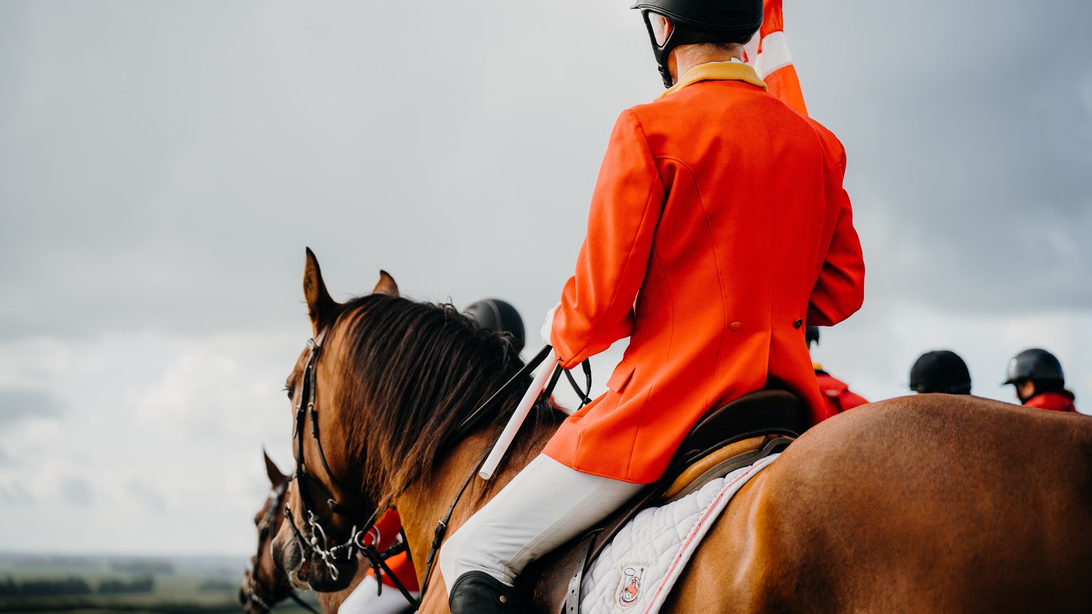 Equestrian cavalry in traditional red blazers riding horses outdoors, showcasing equestrian skills and traditions.