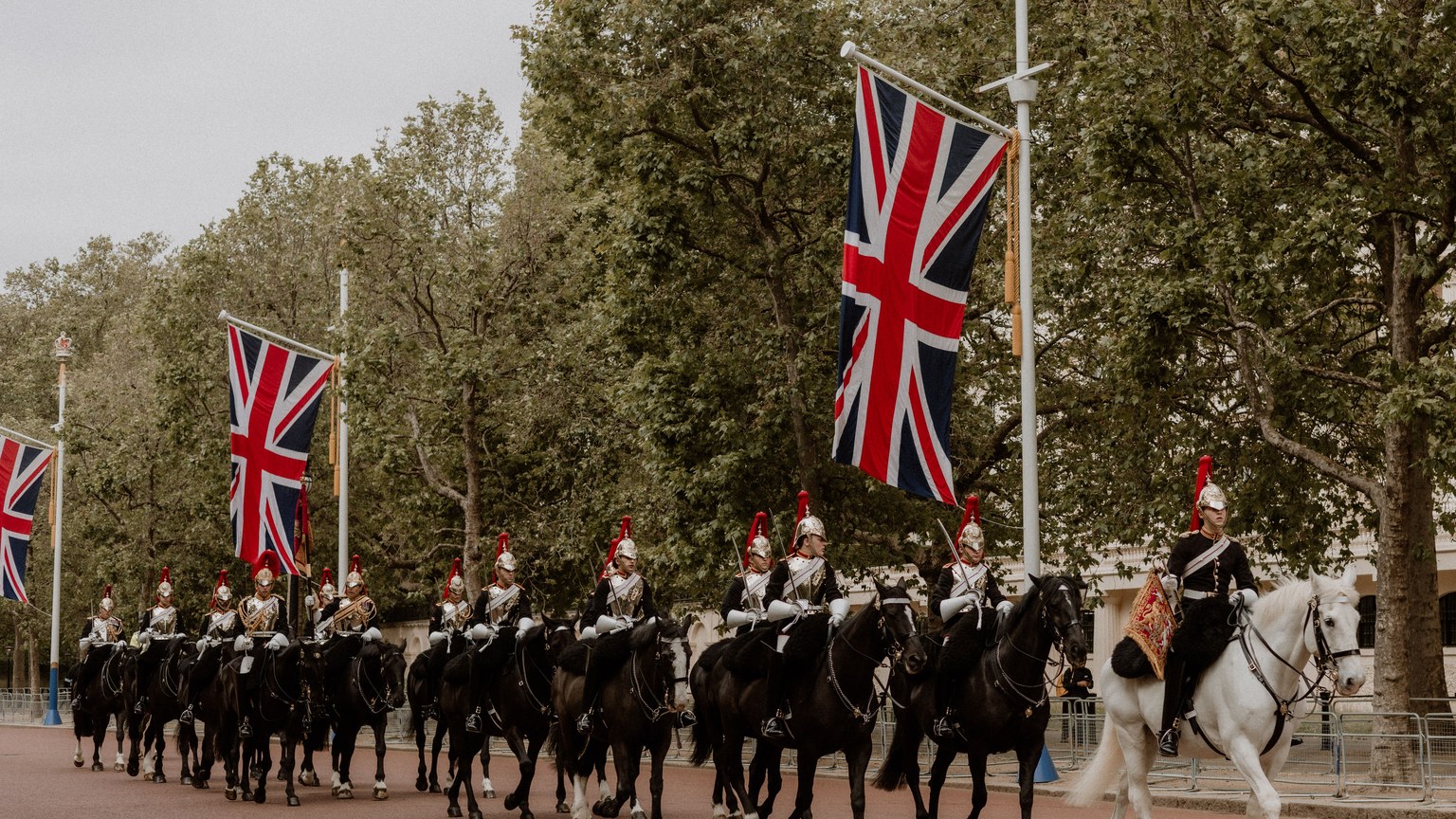 Ceremonial cavalry with Union Flags in a historical parade on The Mall, London.