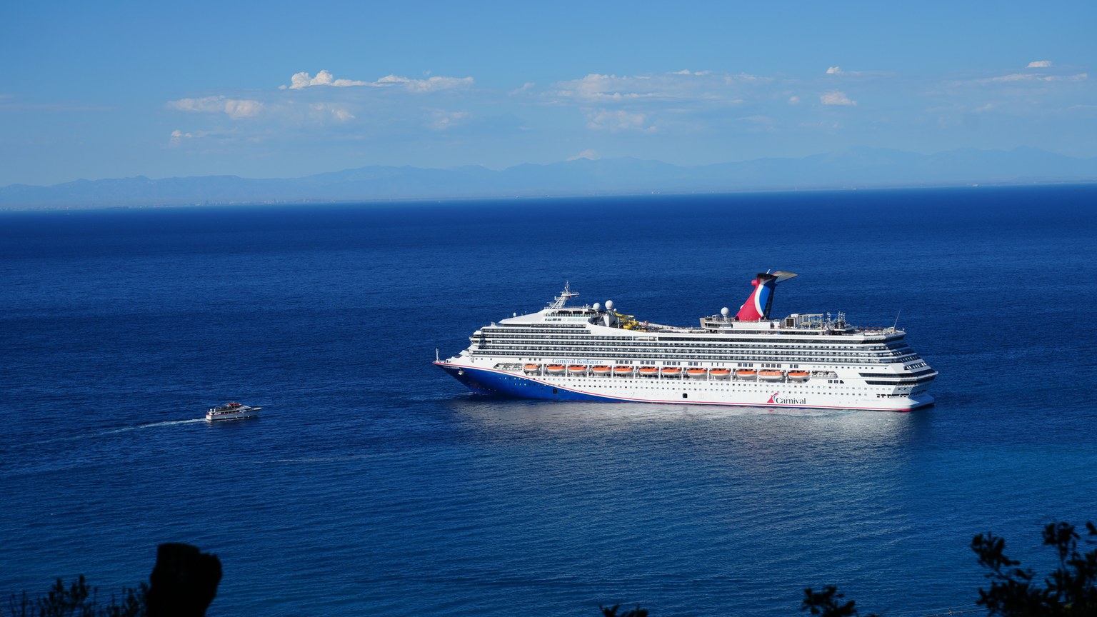 Stunning view of a luxury cruise ship navigating the calm blue ocean under a clear sky.