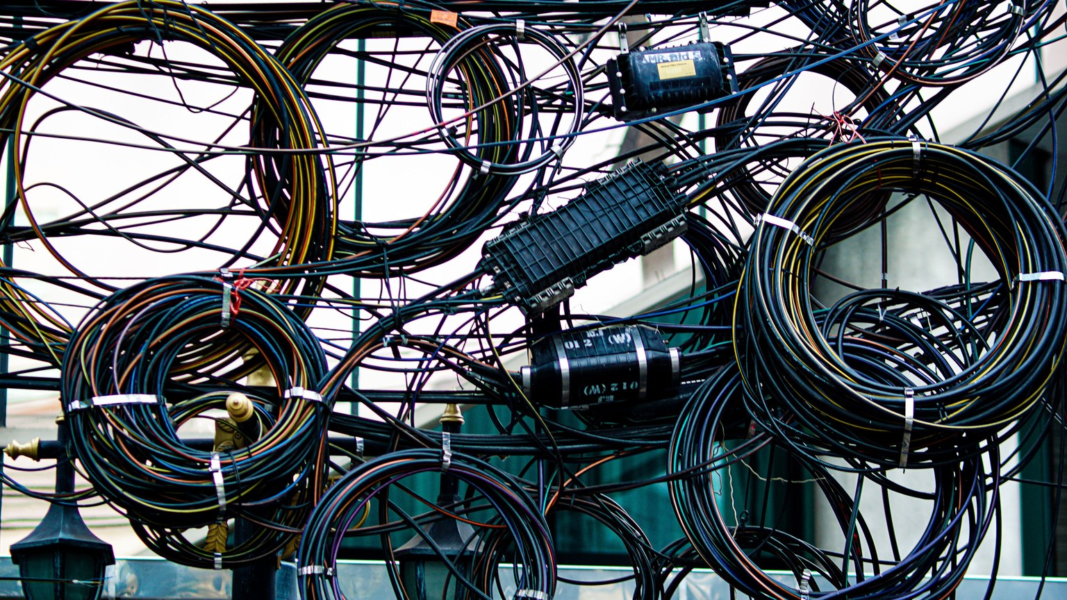 Intricate network of tangled power and communication cables outdoors.
