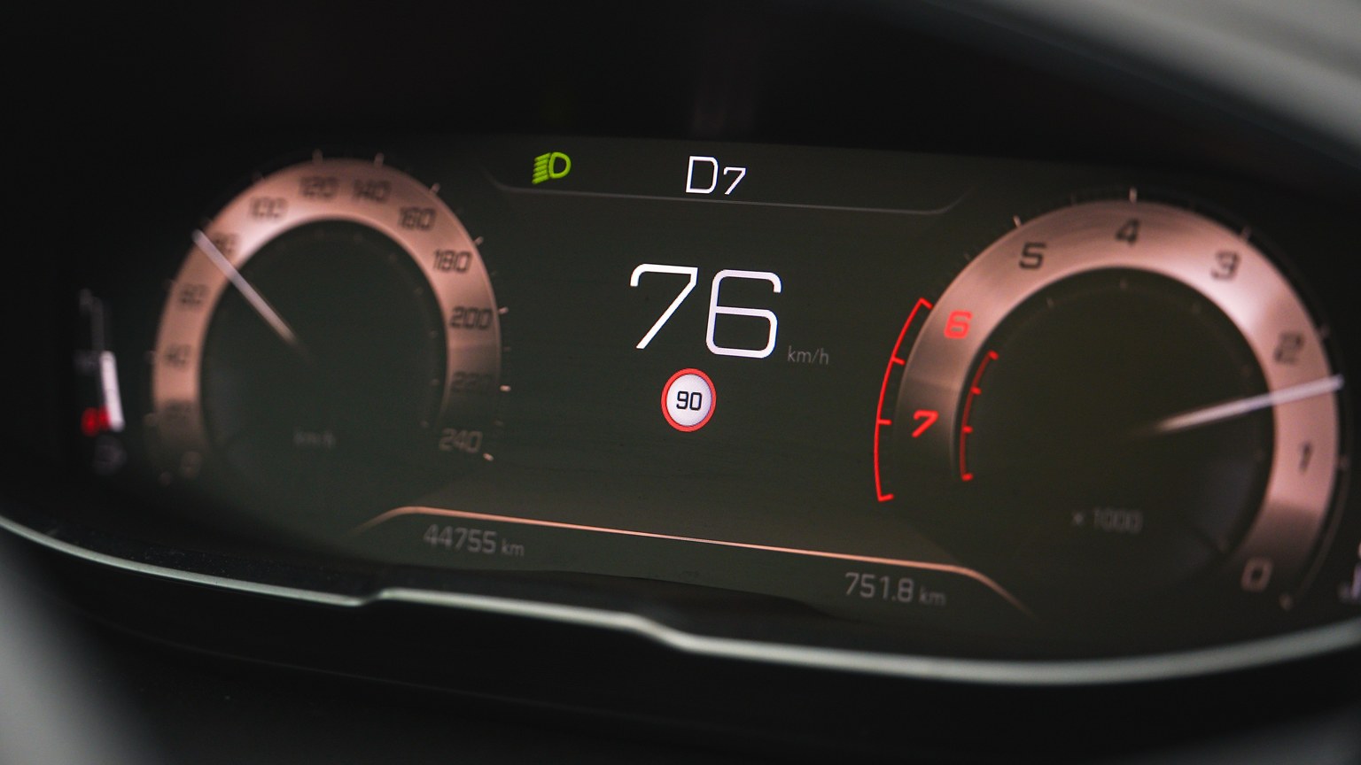 Close-up of a car speedometer display reading 76 km/h with a digital dashboard interface.