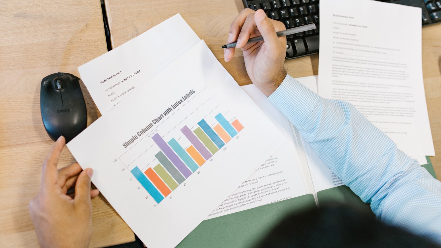 A business analyst reviews a colorful bar chart and documents at a desk, indicating data analysis.