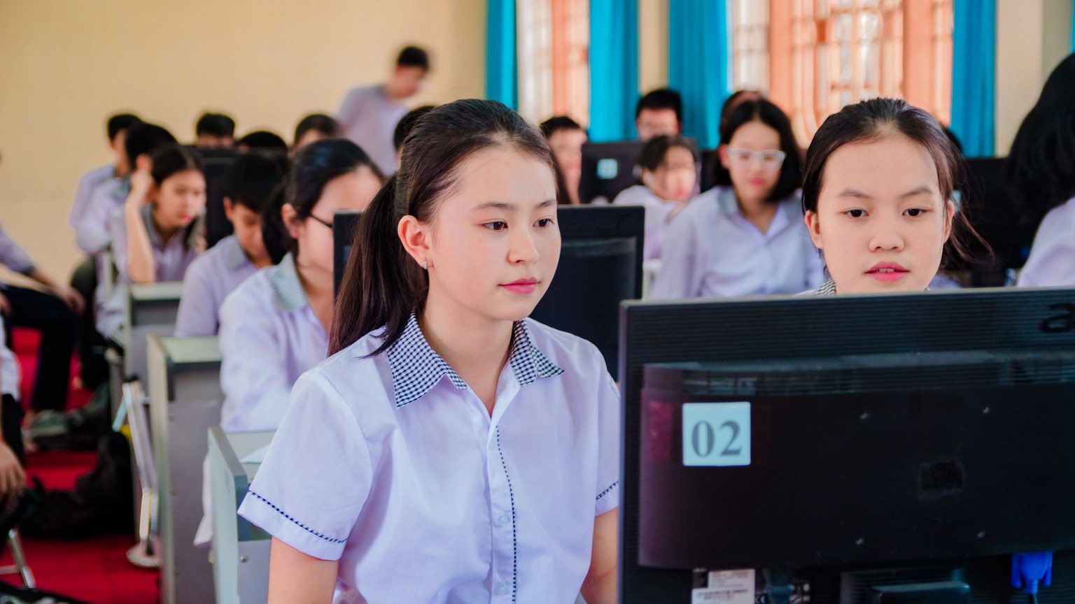 Group of high school students focused on learning in a computer lab setting.