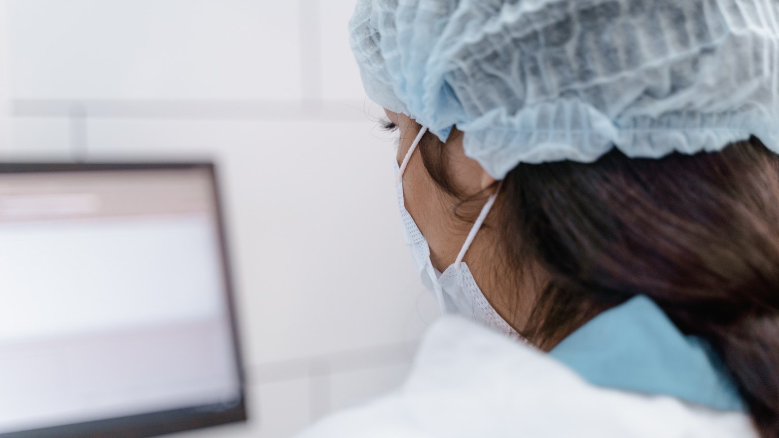 A lab technician wearing protective gear works on data analysis in a modern laboratory environment.