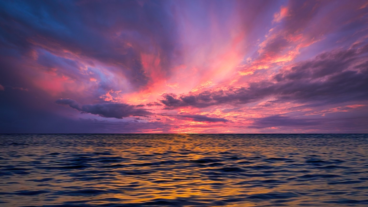 Stunning ocean view at sunset with colorful sky reflecting on the water.