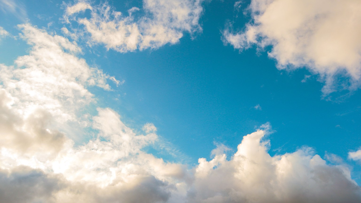 A bright blue sky adorned with fluffy white clouds, creating a peaceful and serene atmosphere.