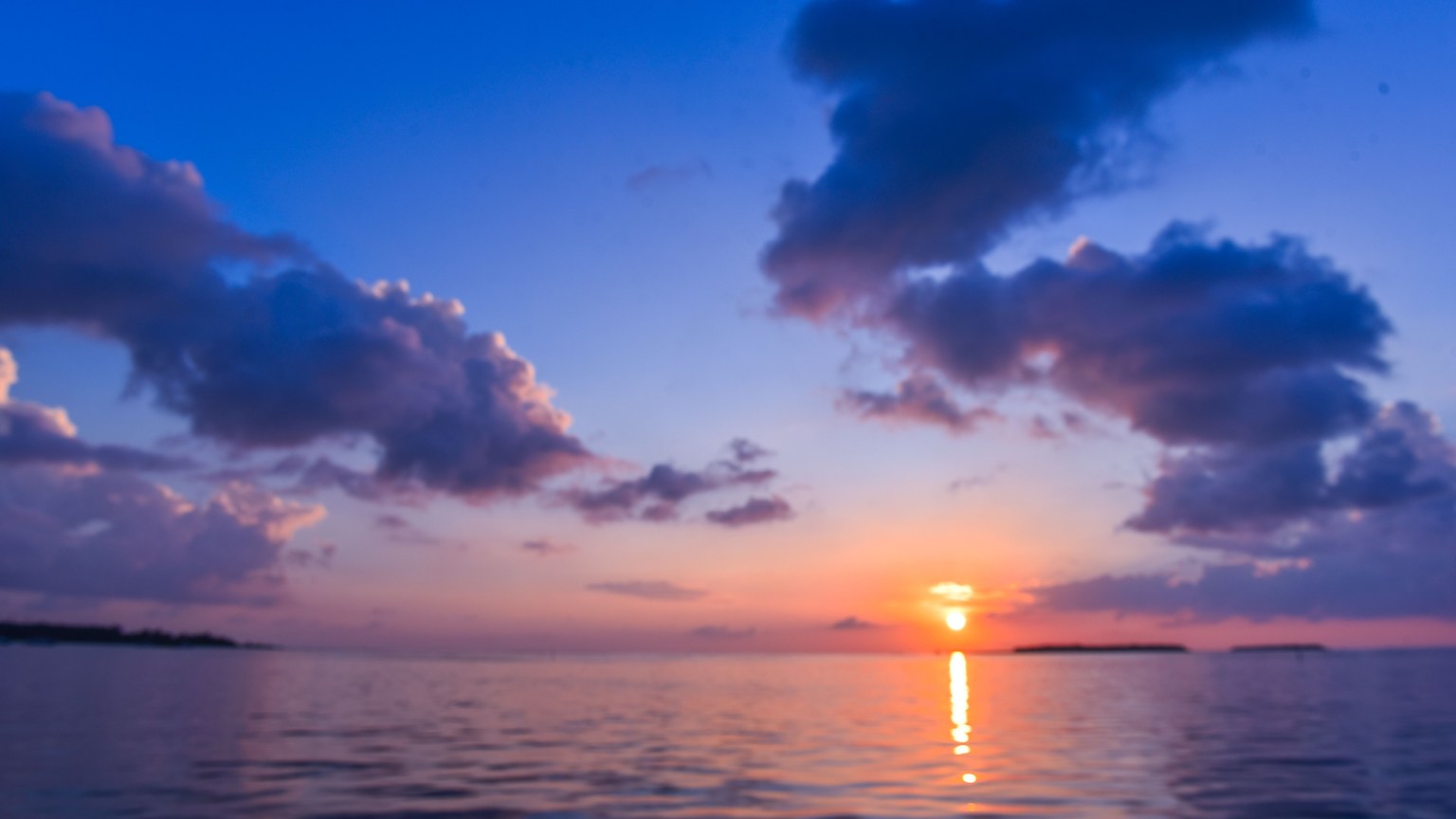 A breathtaking view of a tropical sunset with vibrant colors reflecting on the calm sea.