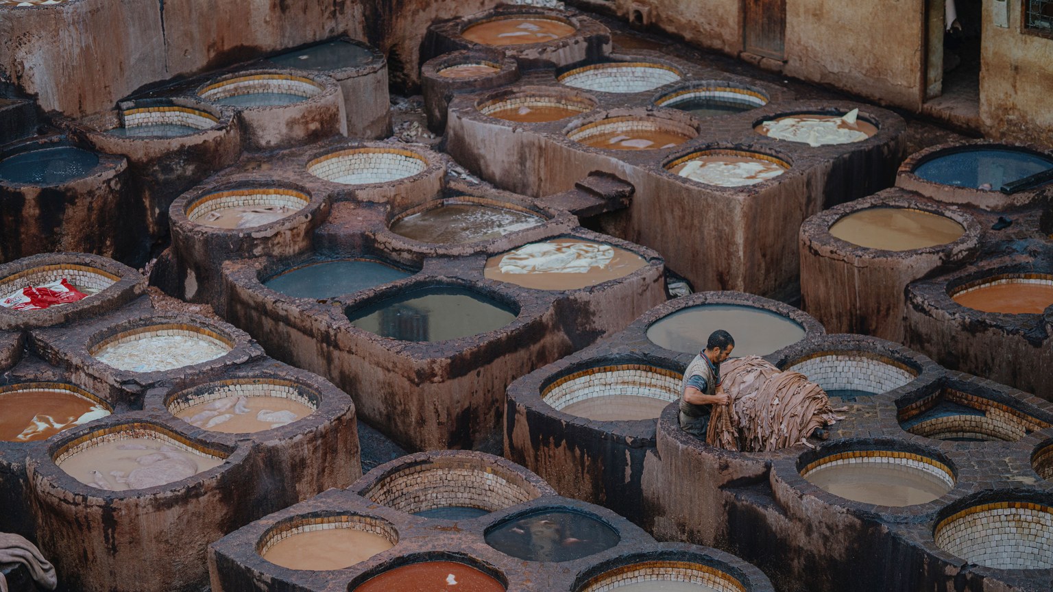 Aerial view of a traditional leather tannery in Fes, Morocco, showcasing vibrant dye pits.