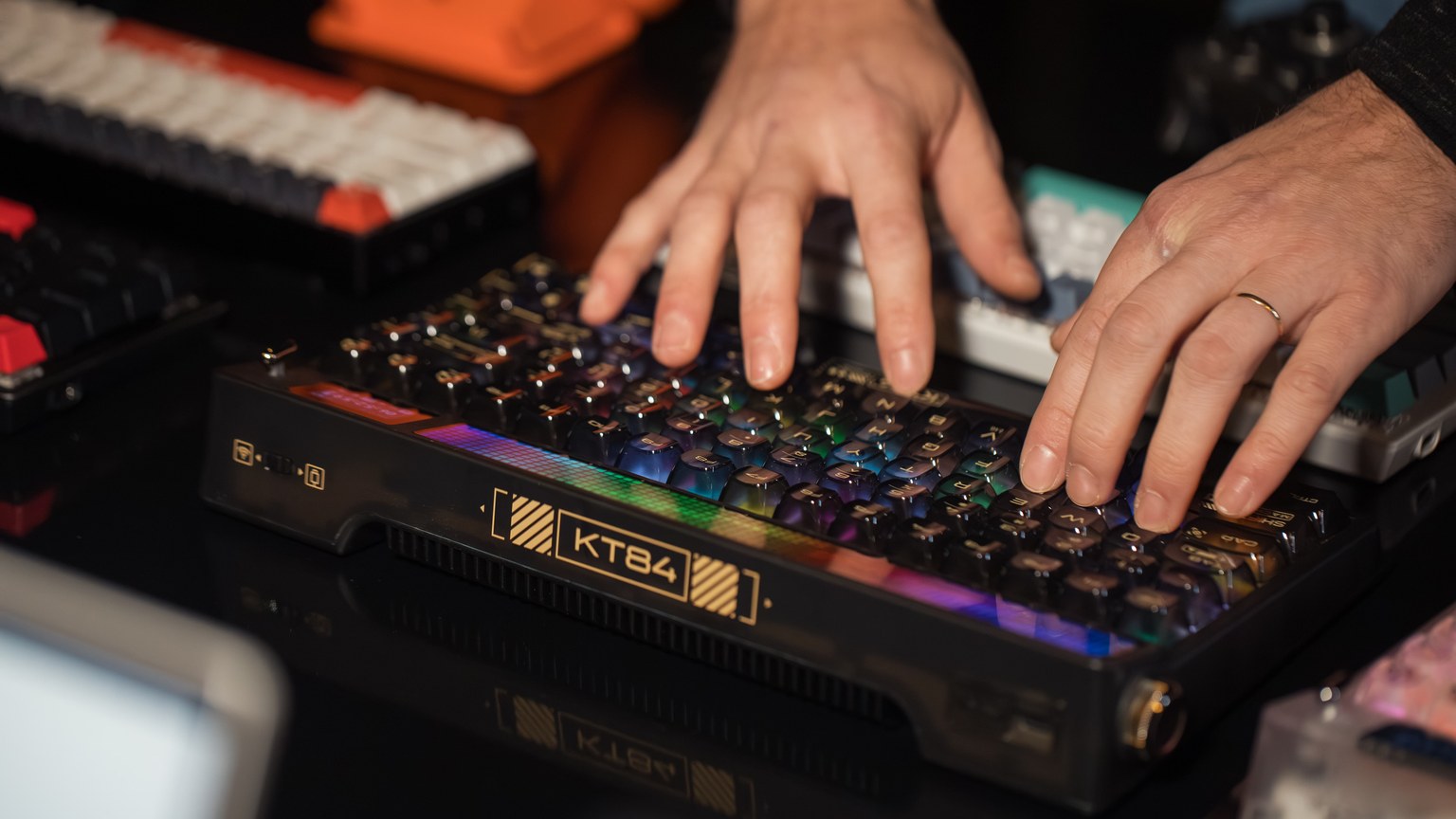 Hands typing on an RGB mechanical keyboard with colorful lights on a desk, creating a vibrant tech scene.