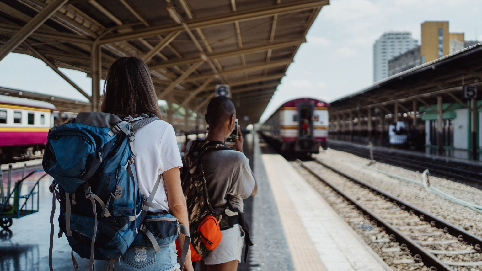 Two backpackers waiting at a railway station, ready for their travel adventure.