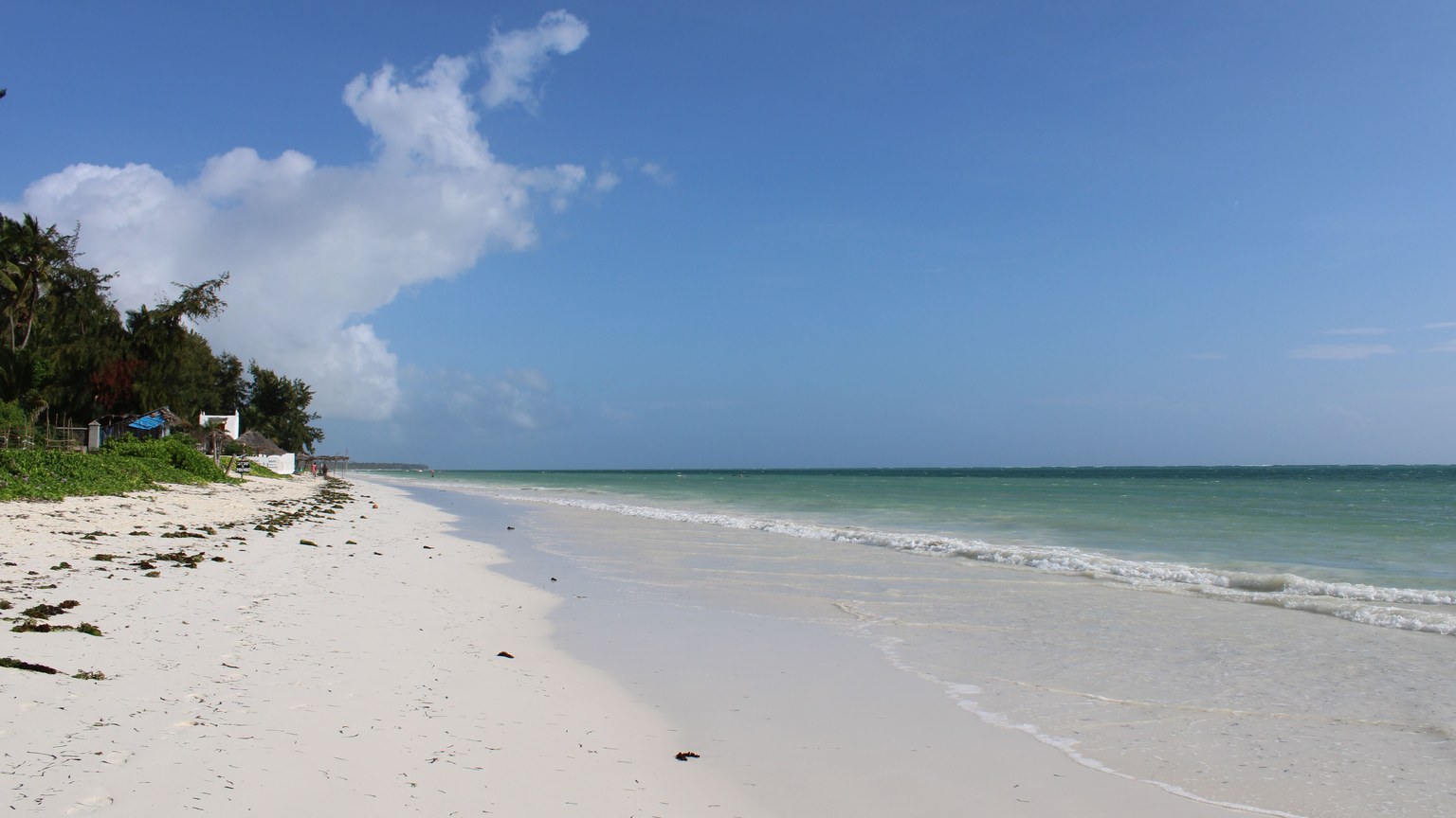 Idyllic white sand beach and azure ocean under clear skies in Zanzibar, Tanzania.