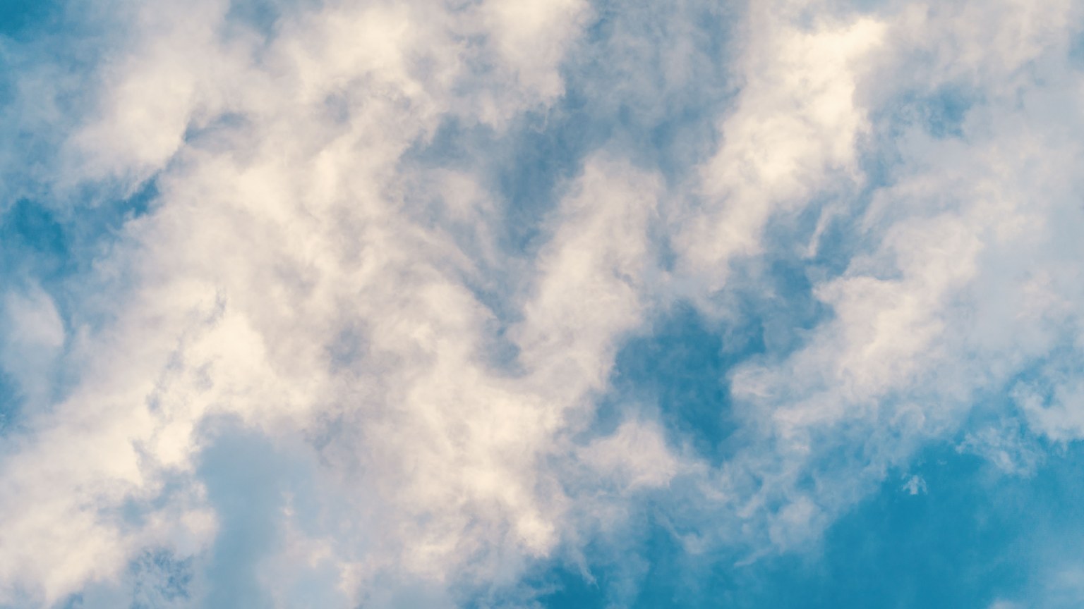A serene view of fluffy clouds against a bright blue sky, perfect for peaceful and airy concepts.