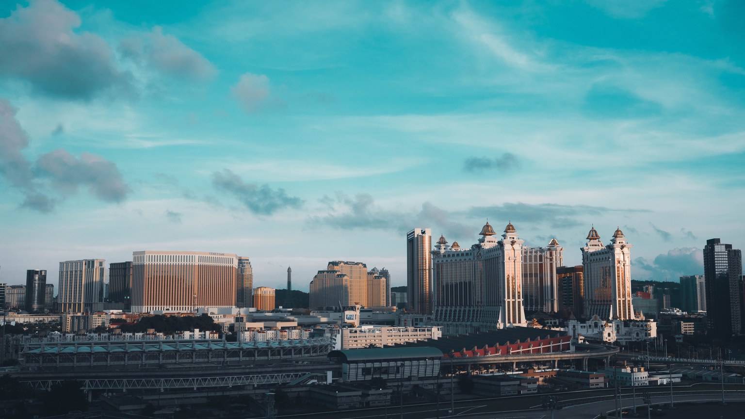 A stunning aerial view of Macau's skyline under a bright blue sky, featuring iconic casino architecture.