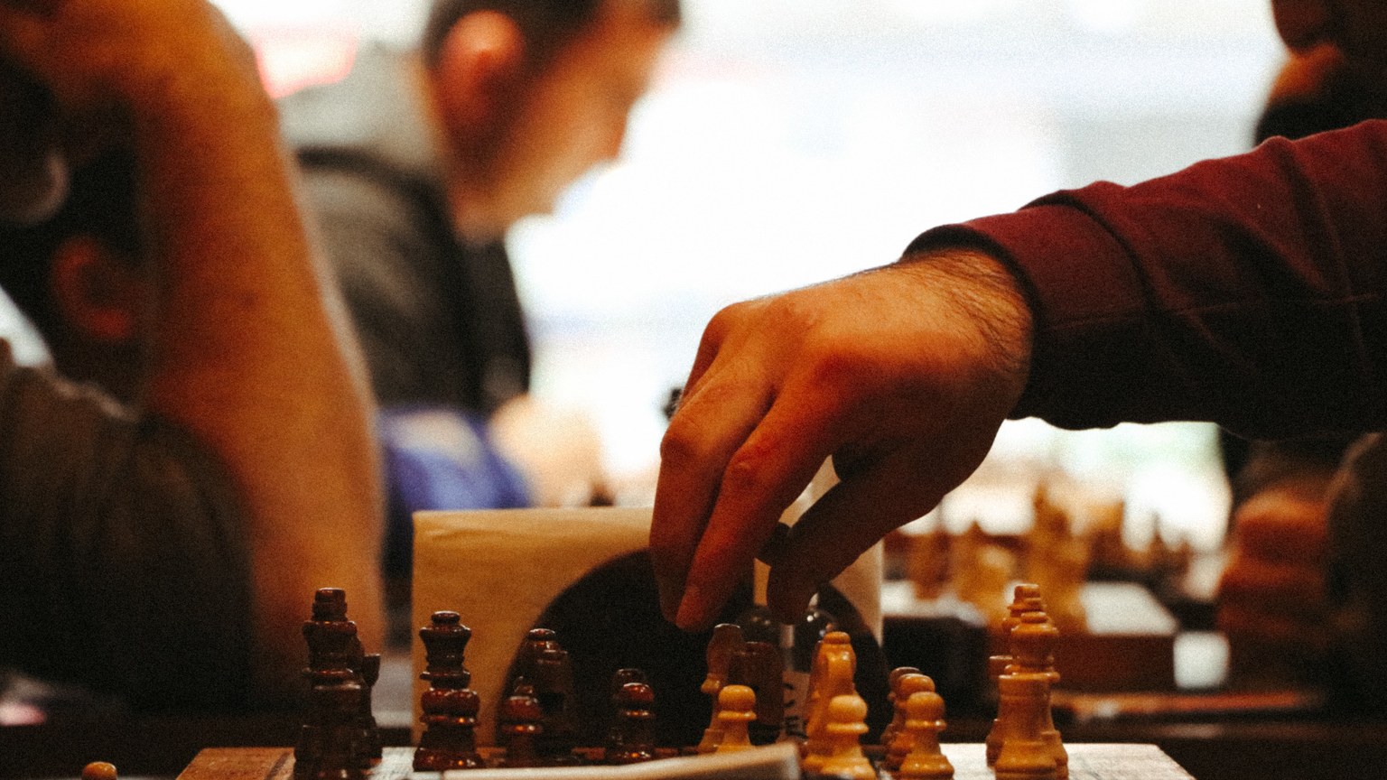 Close-up of a hand moving a chess piece during an intense game.