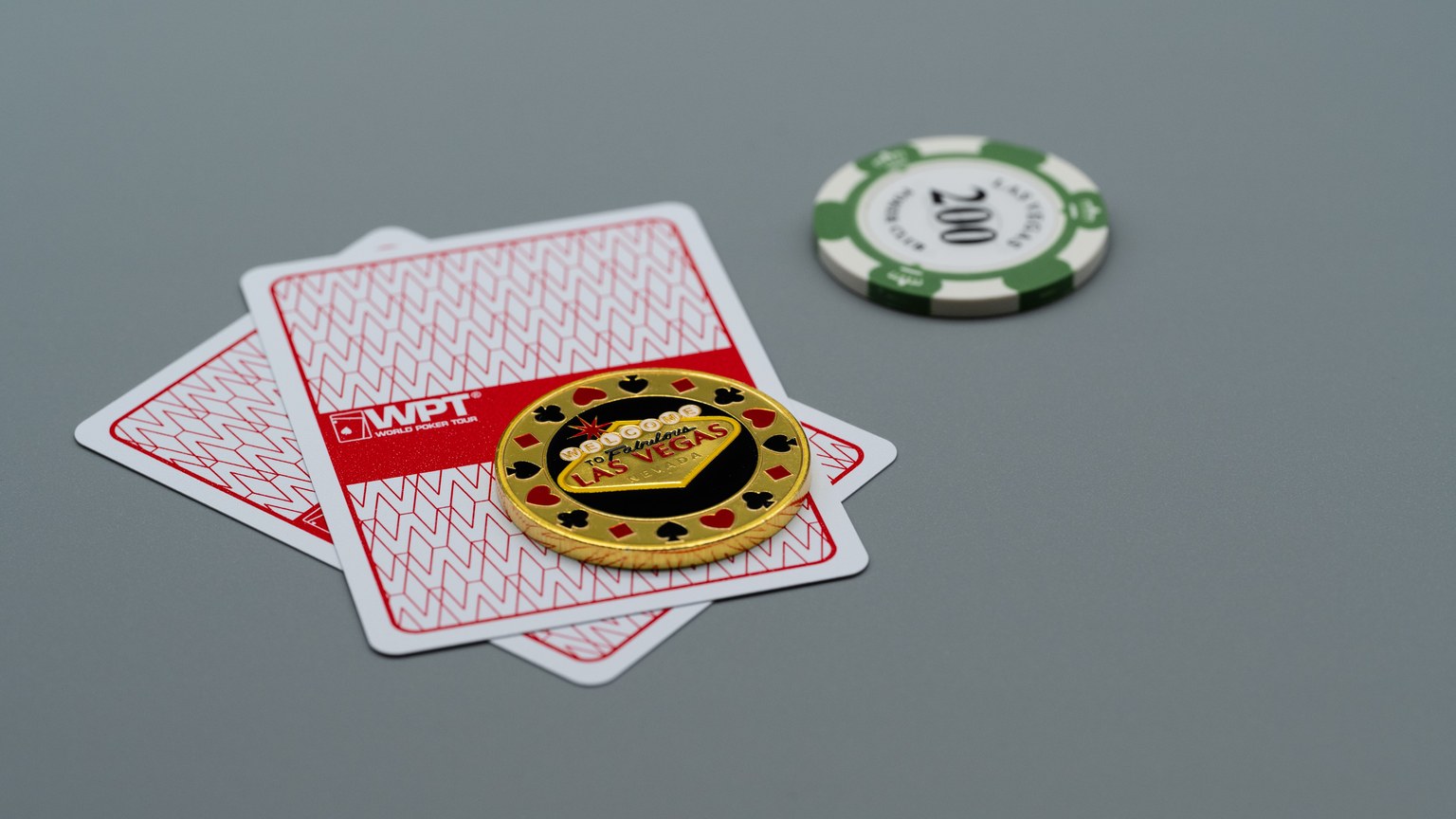 Two playing cards and poker chips, including a Las Vegas chip, on a grey background. Ideal for casino or gambling themes.