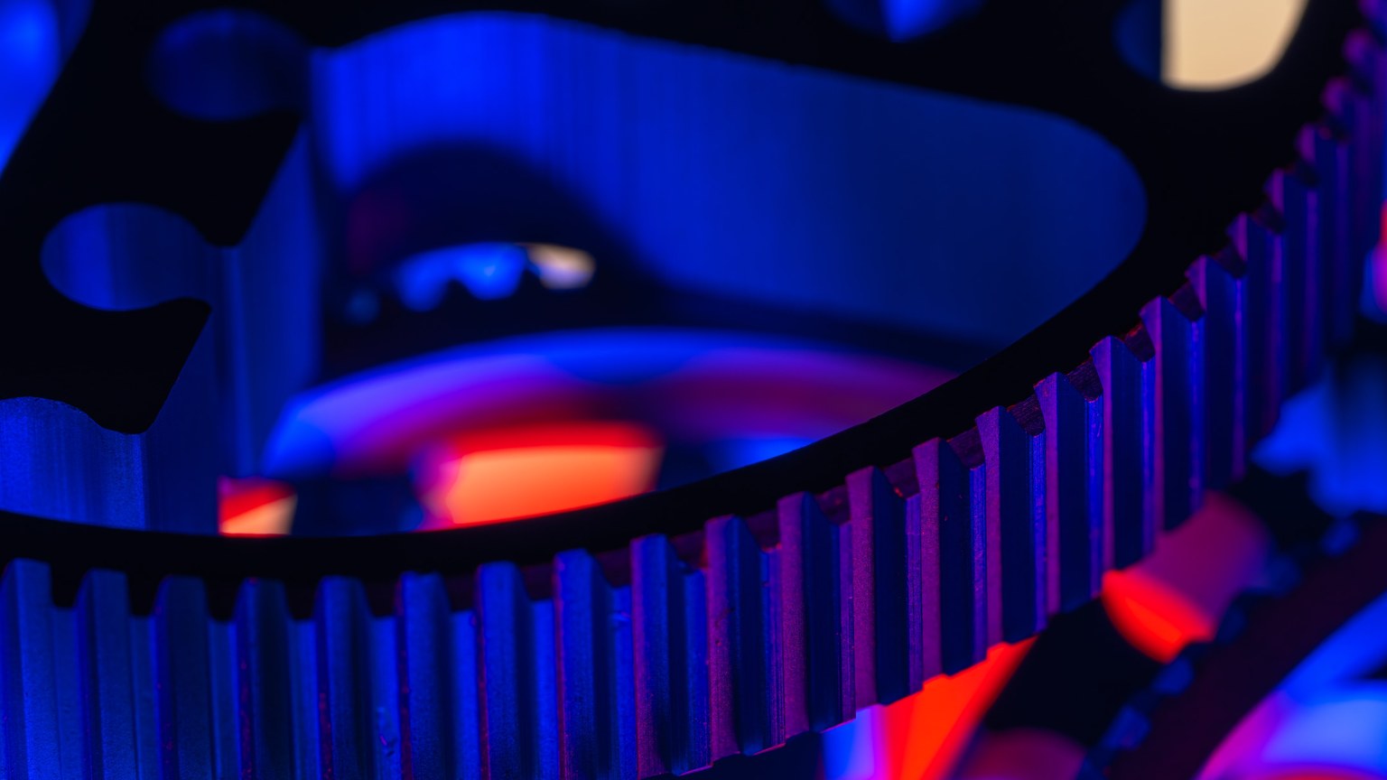 Macro view of metallic gears with striking blue and red lighting showcasing precision engineering.