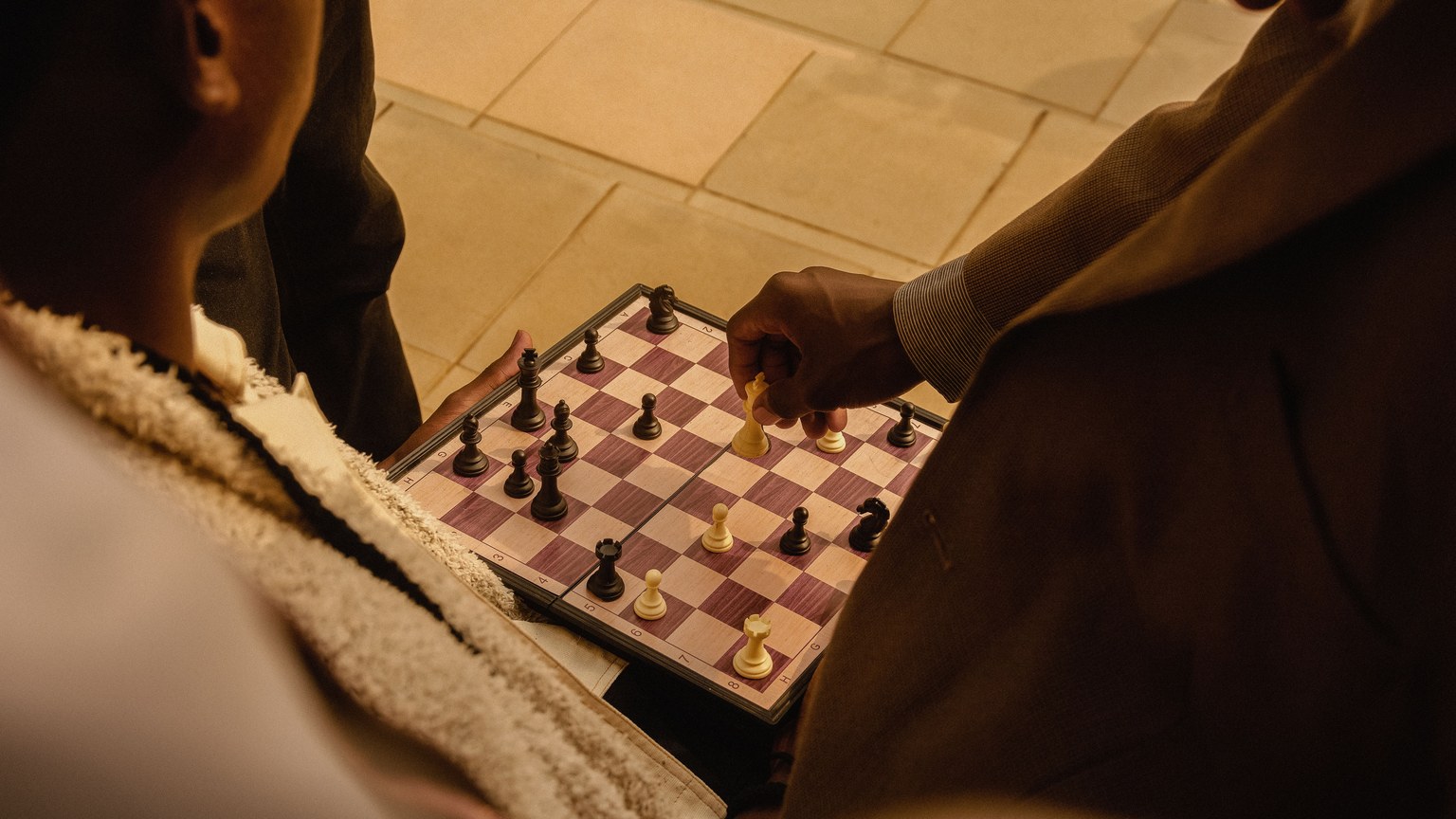 Adults playing chess outdoors in Ado Ekiti, Nigeria, showcasing strategy and leisure.
