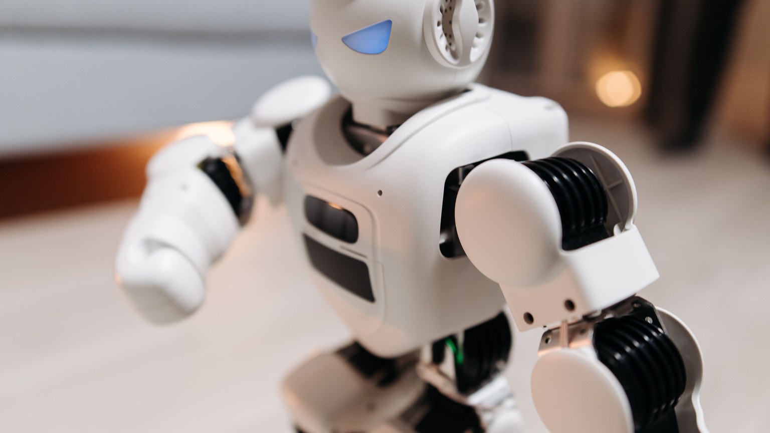 Close-up of a futuristic toy robot with blue eyes, showcasing modern technology indoors.
