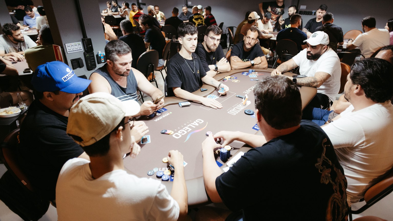 A group of adult men engage in a lively poker game at a vibrant casino setting.