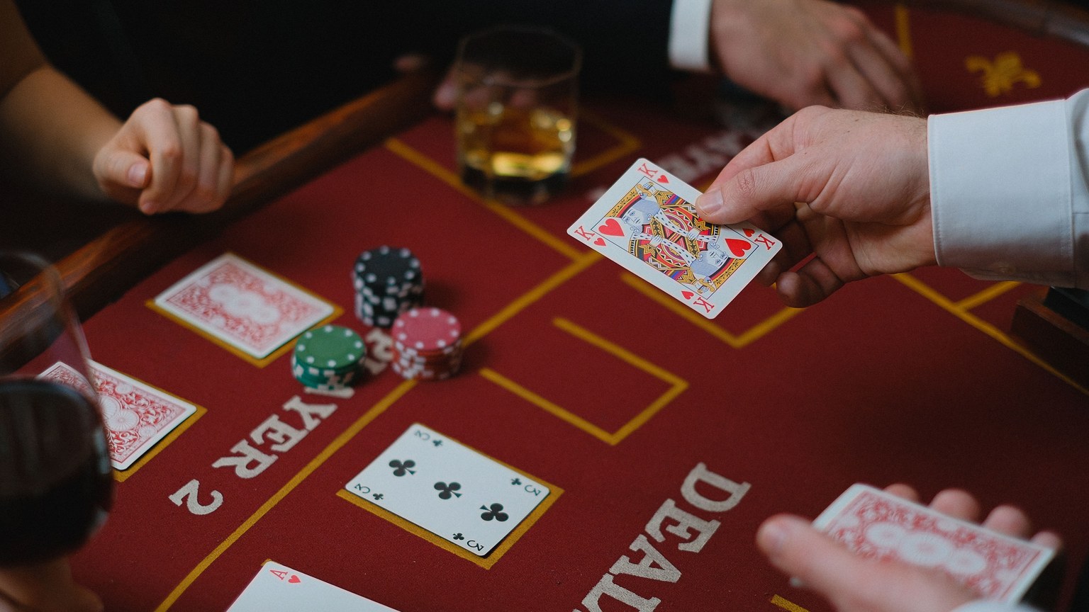 Close-up view of a casino game with cards and chips on the table, featuring player interaction.