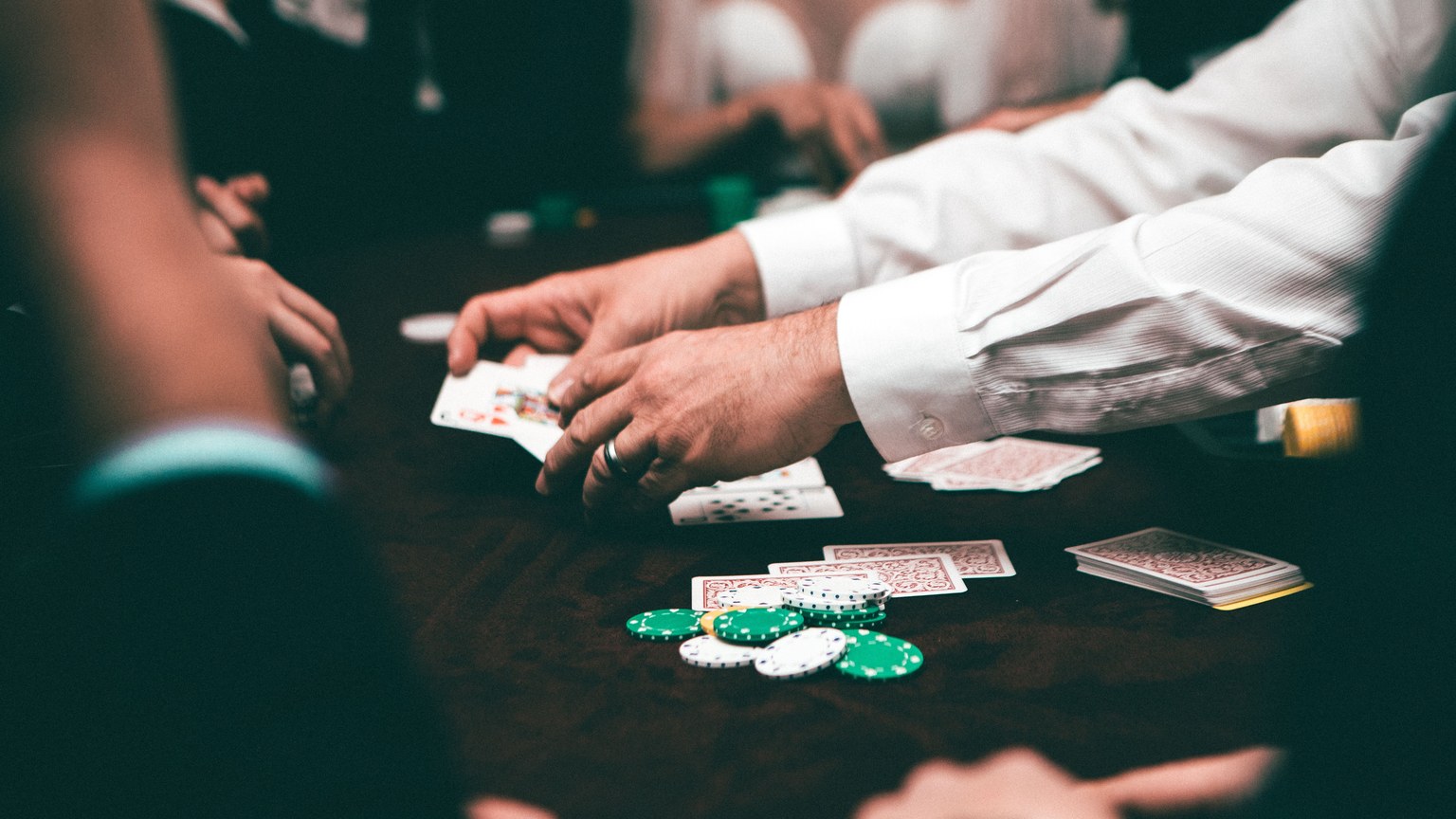 An intense poker game featuring players and poker chips on the table in an indoor setting.