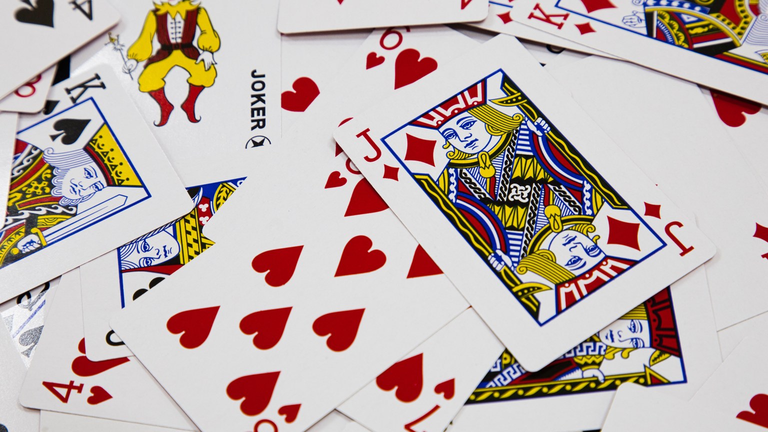 A vibrant arrangement of playing cards depicting various suits and a joker in a dynamic composition.