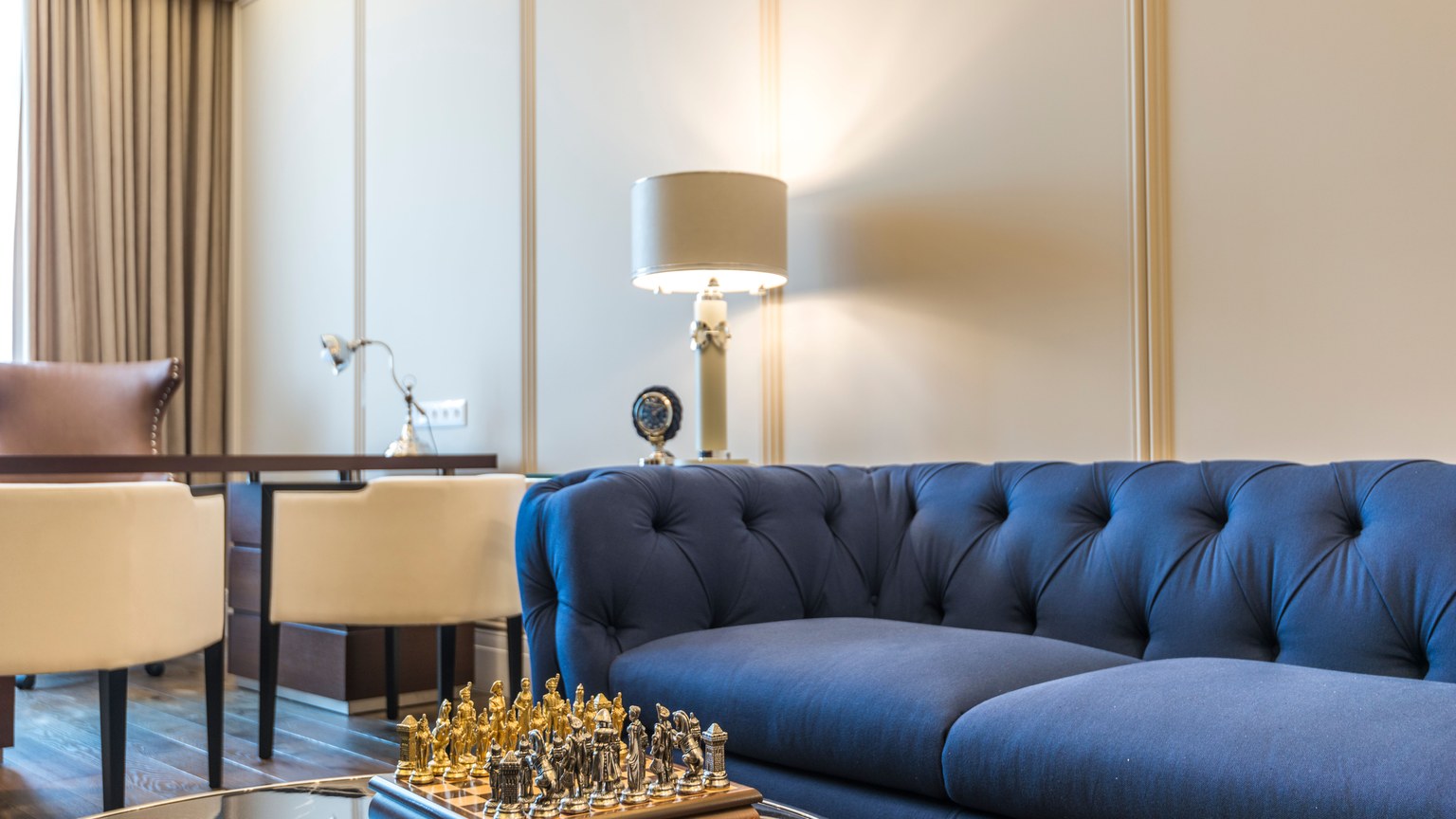 Stylish living room featuring a blue couch, chess set, lamps, and modern decor.