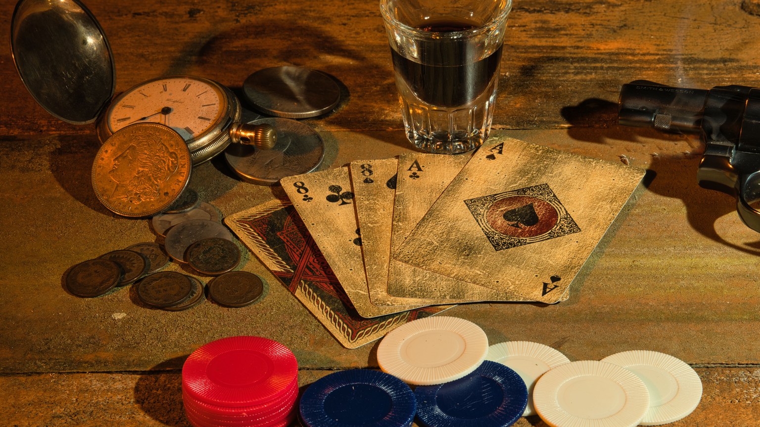 A vintage-themed still life featuring playing cards, poker chips, coins, a revolver, and a pocket watch.