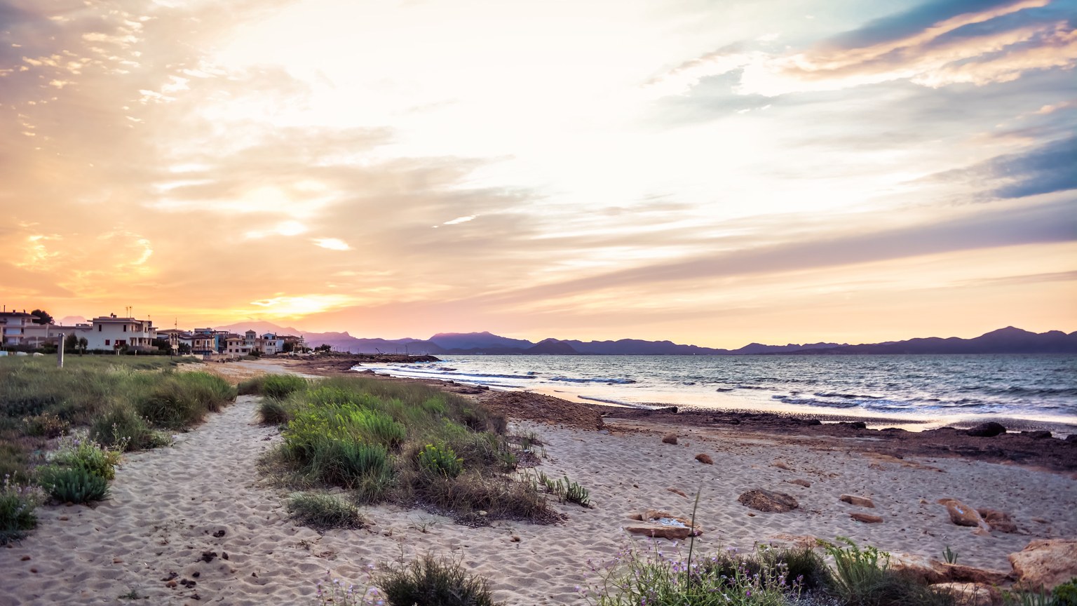 Captivating beach landscape at sunset with vibrant skies, gentle waves, and tranquil surroundings.