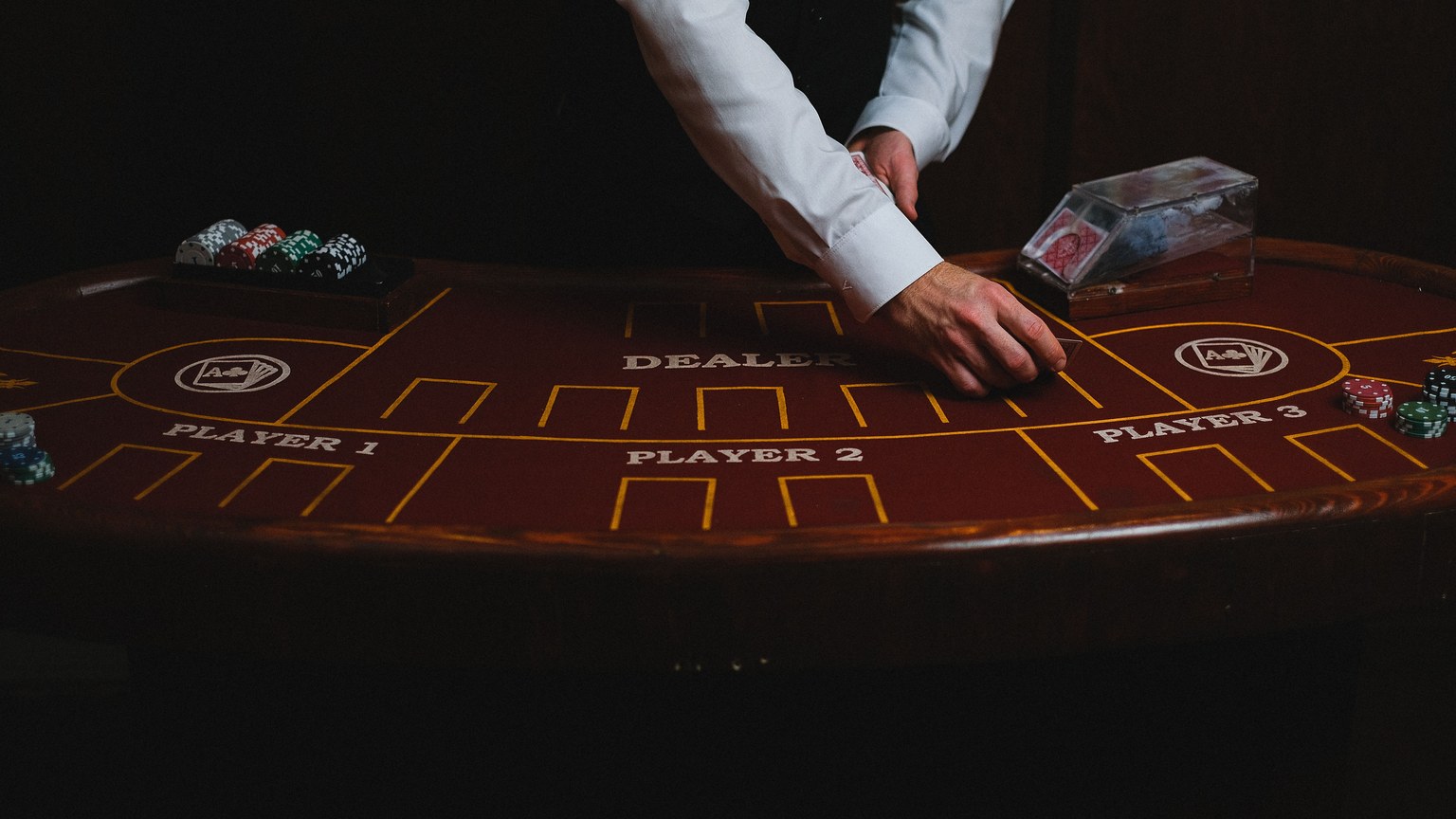 A croupier deals cards on a dimly lit casino table, showcasing gambling atmosphere.