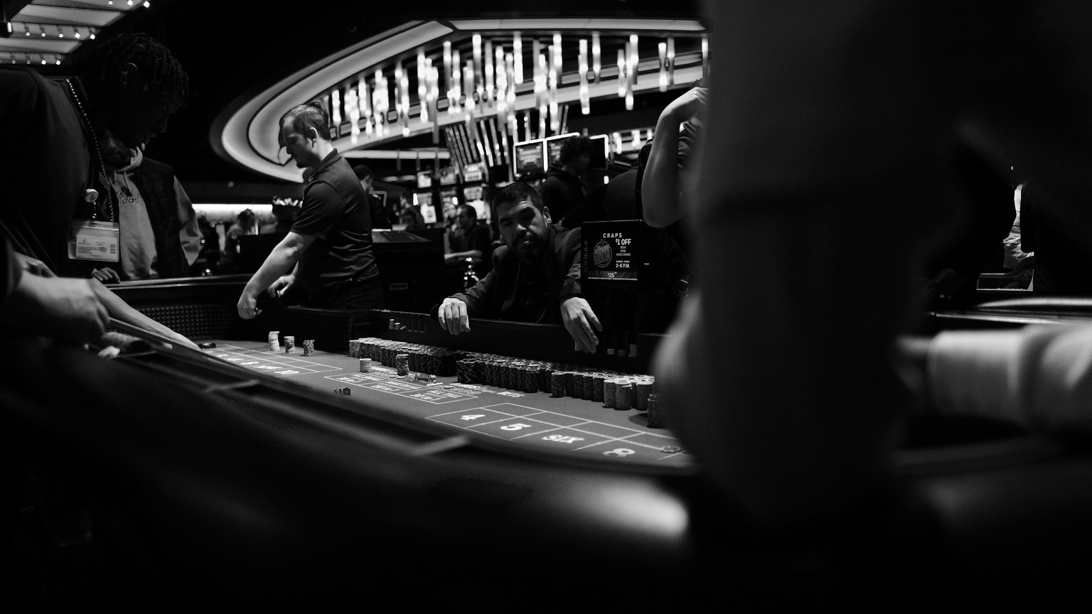 High-stakes gambling at a casino craps table in black and white.