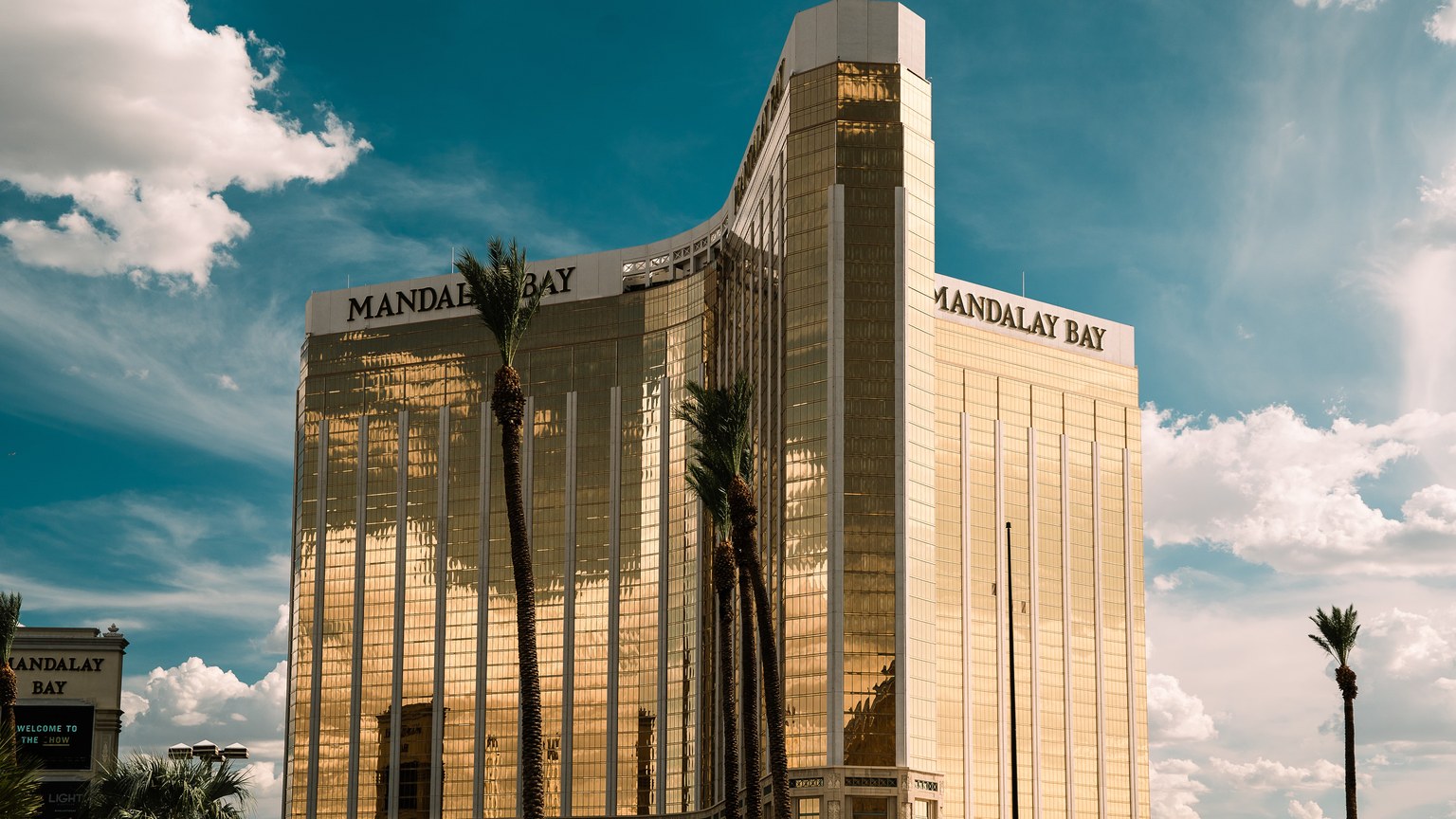 The iconic Mandalay Bay Hotel in Las Vegas shines brightly against a clear blue sky.