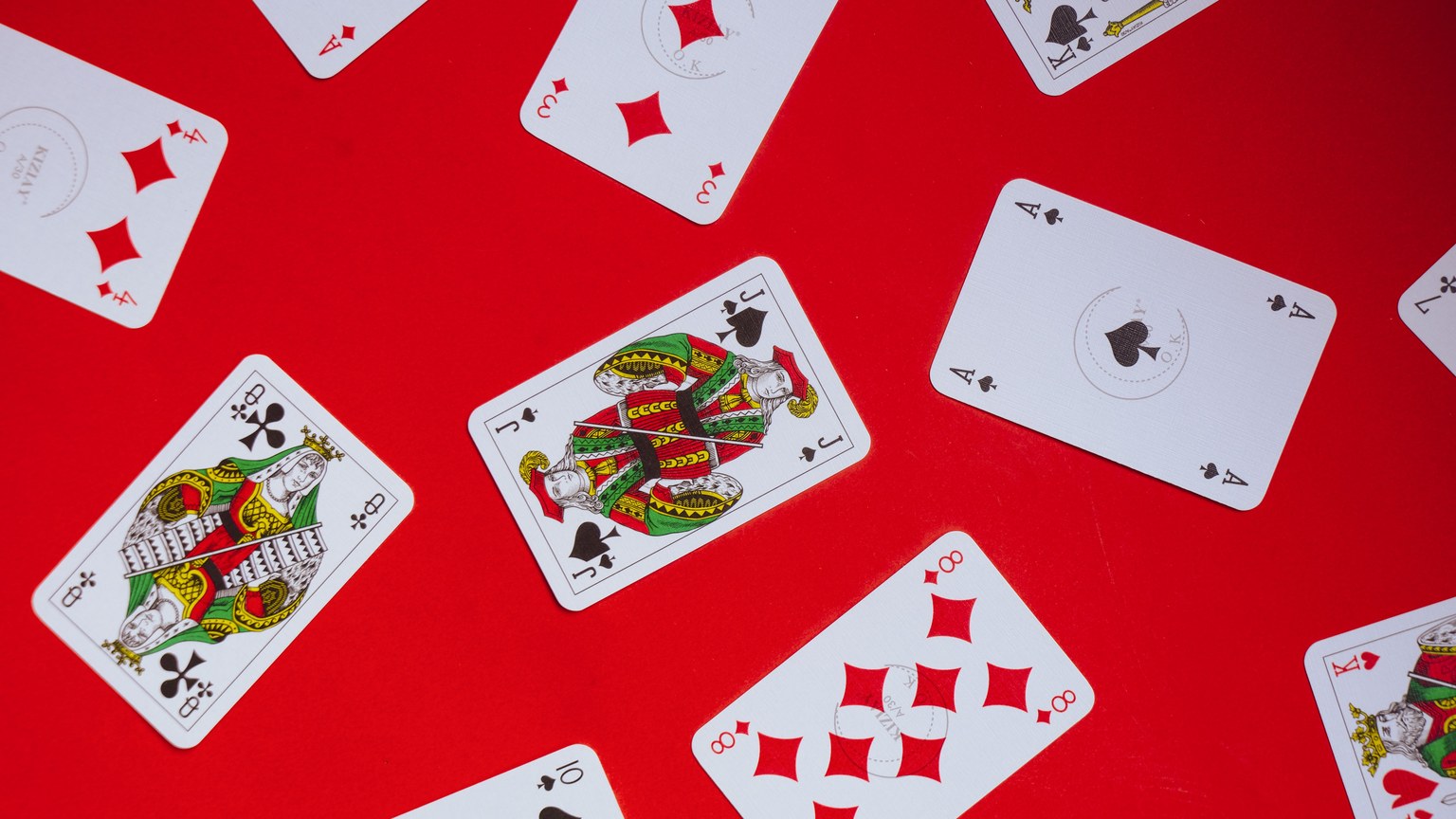 Scattered playing cards on a vibrant red background, perfect for themes of gaming and chance.
