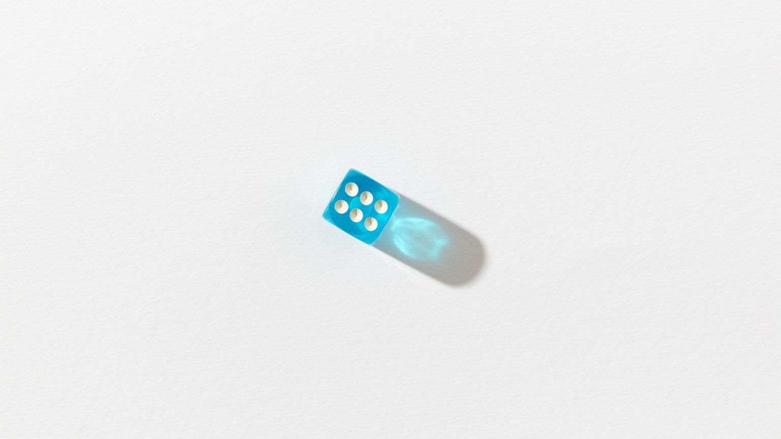 Minimalist photo of a blue dice set against a white background with shadow, creating a stark contrast.